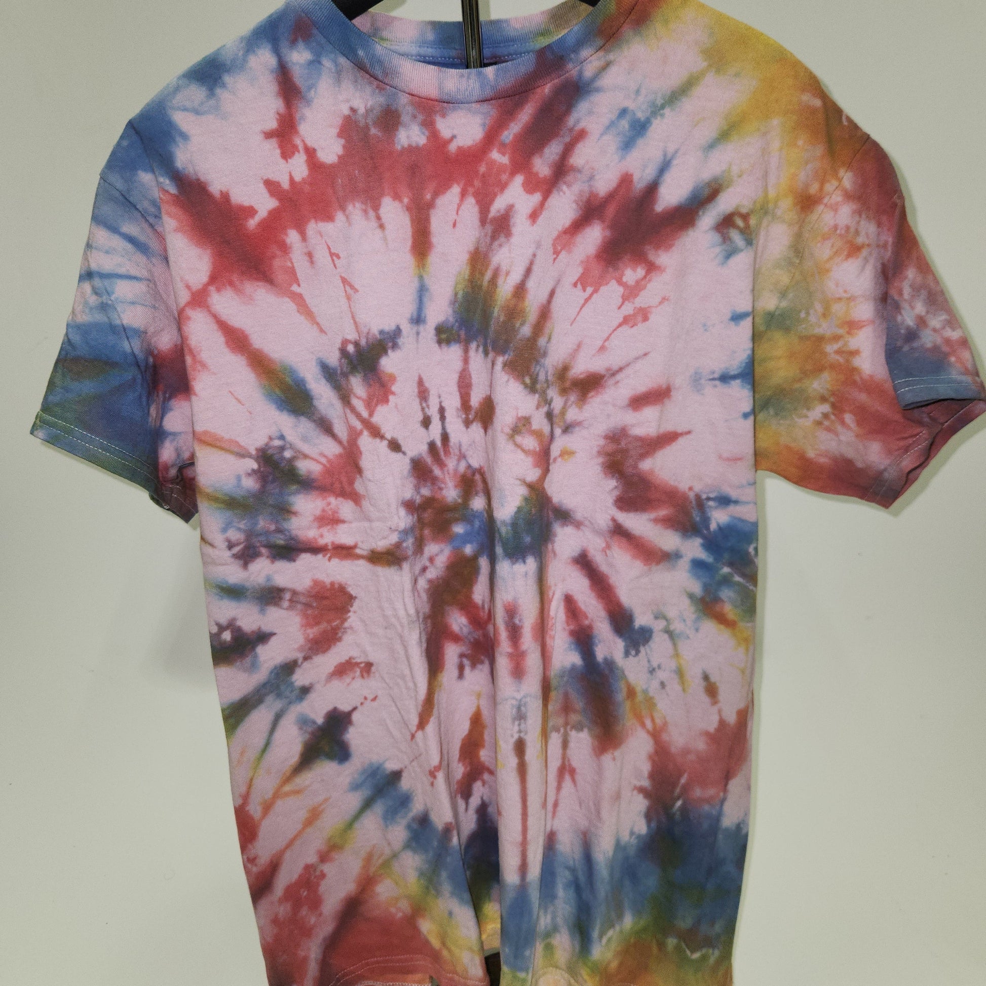 Tie-dye shirt on a hanger with a plain background
